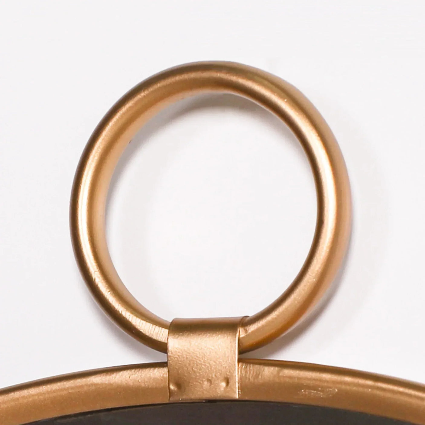 Gold metal wall mirror hanging ring close-up against white background