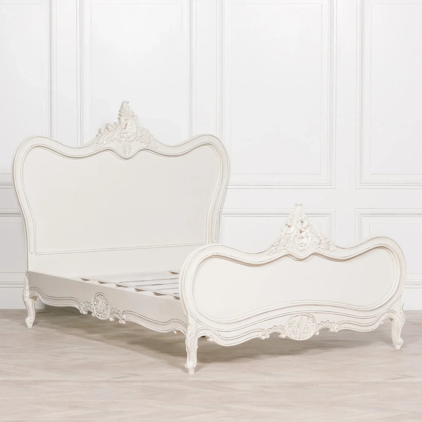 Ivory wooden bed frame with ornate carved headboard and footboard on light wood floor