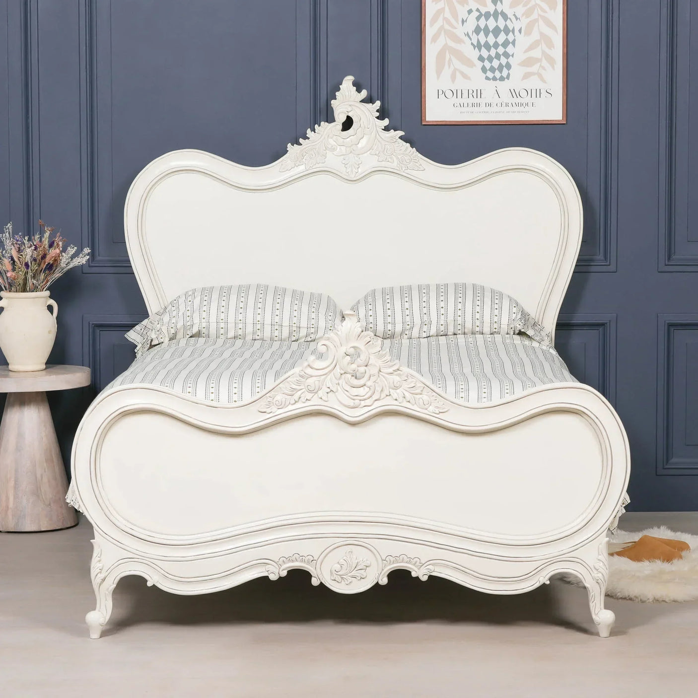 White French style bed with ornate carved headboard and footboard in classic bedroom