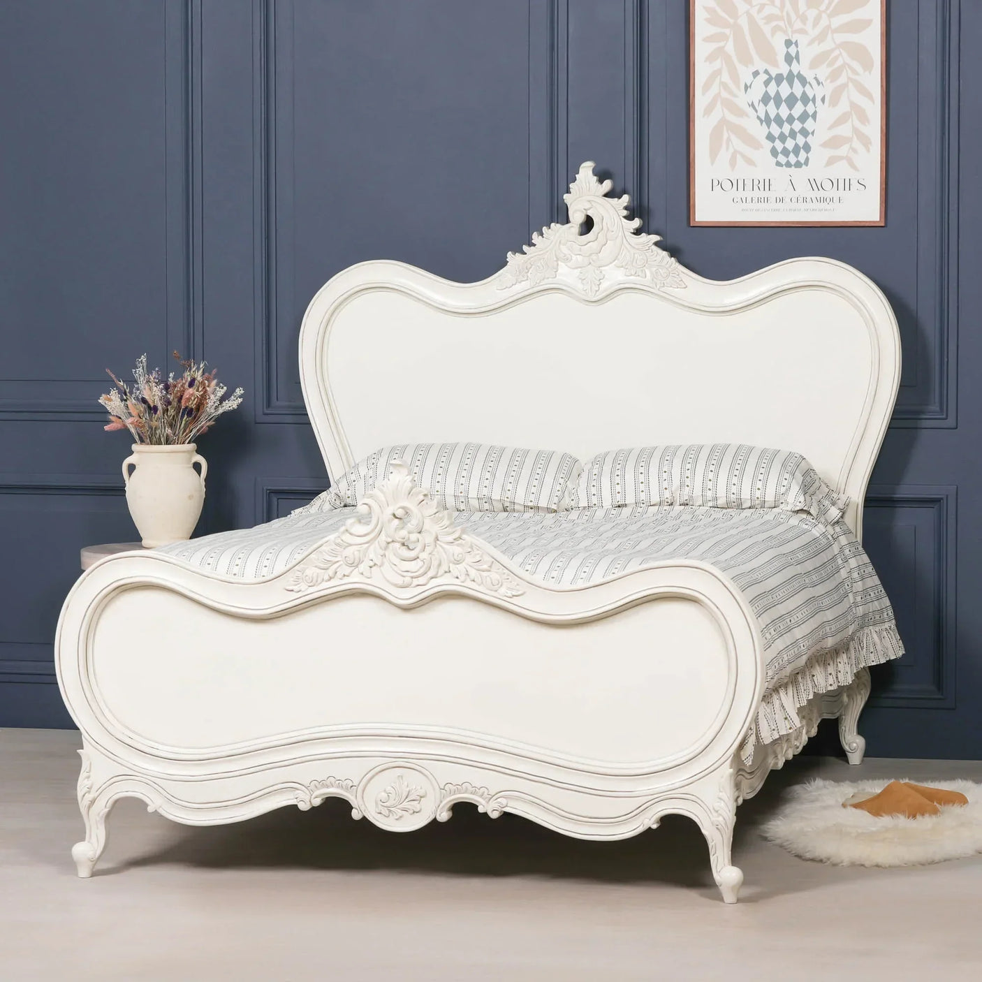 White French style carved bed with patterned bedding in a navy paneled bedroom