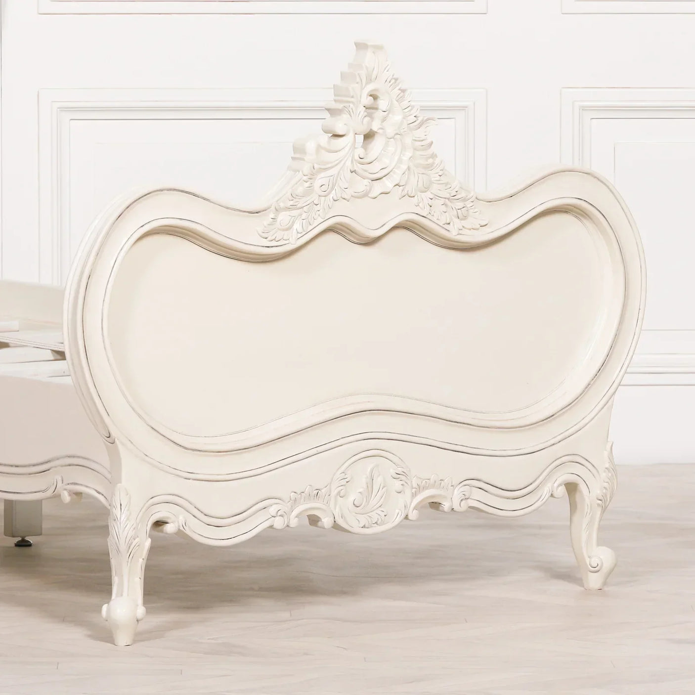 Cream wood bed frame with ornate carved detail and curved footboard in classic style