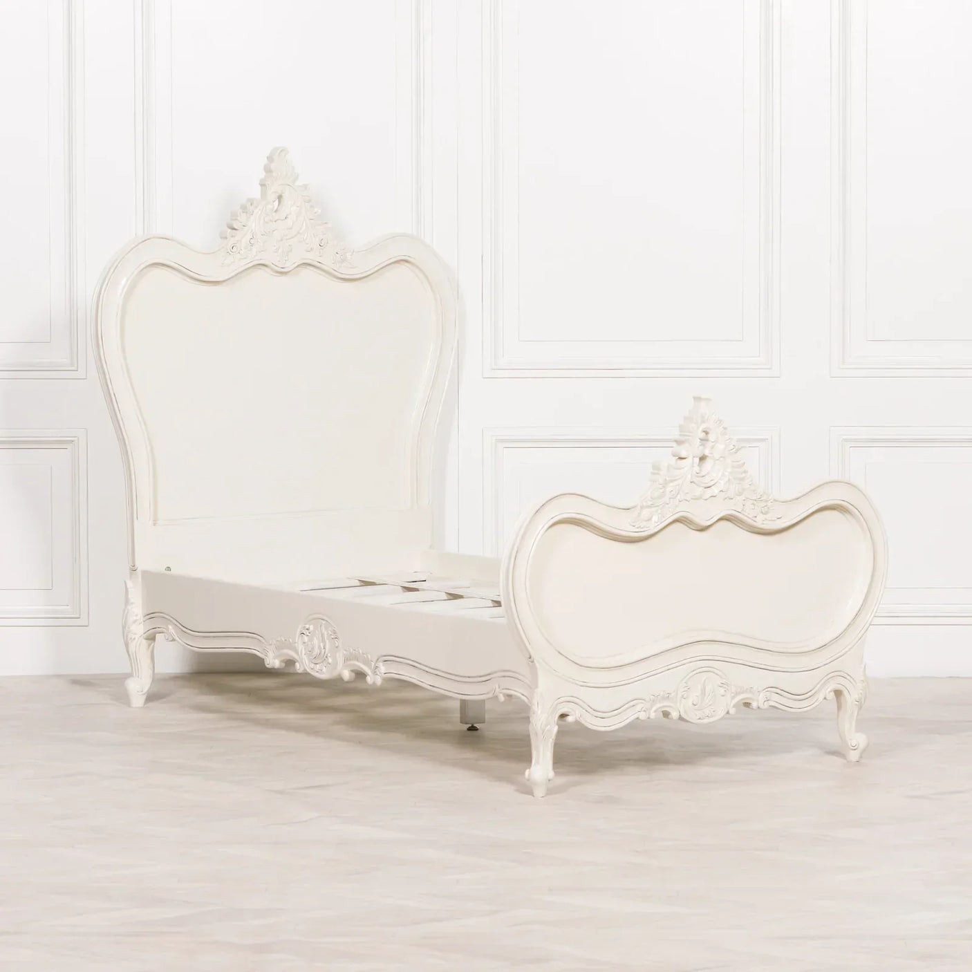 Cream French style bed frame with ornate carved headboard and footboard in bright room