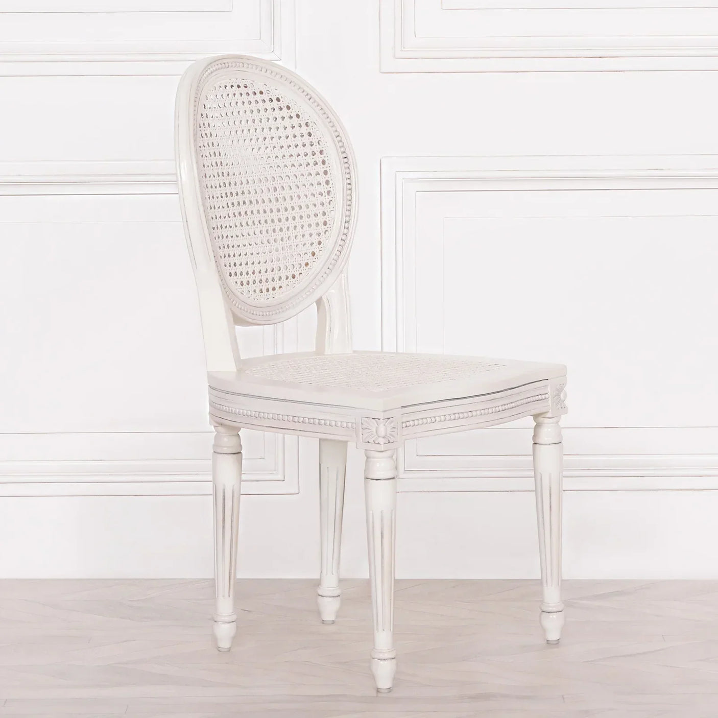White cane back dining chair with carved legs and oval seat, side view