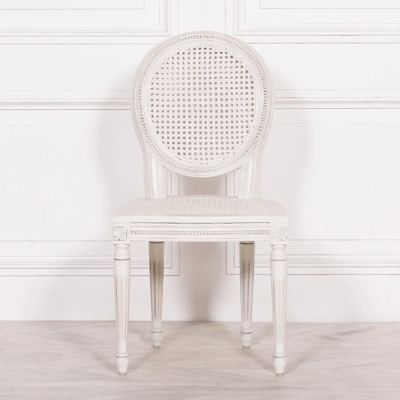 White wooden dining chair with round cane backrest and seat, positioned facing forward