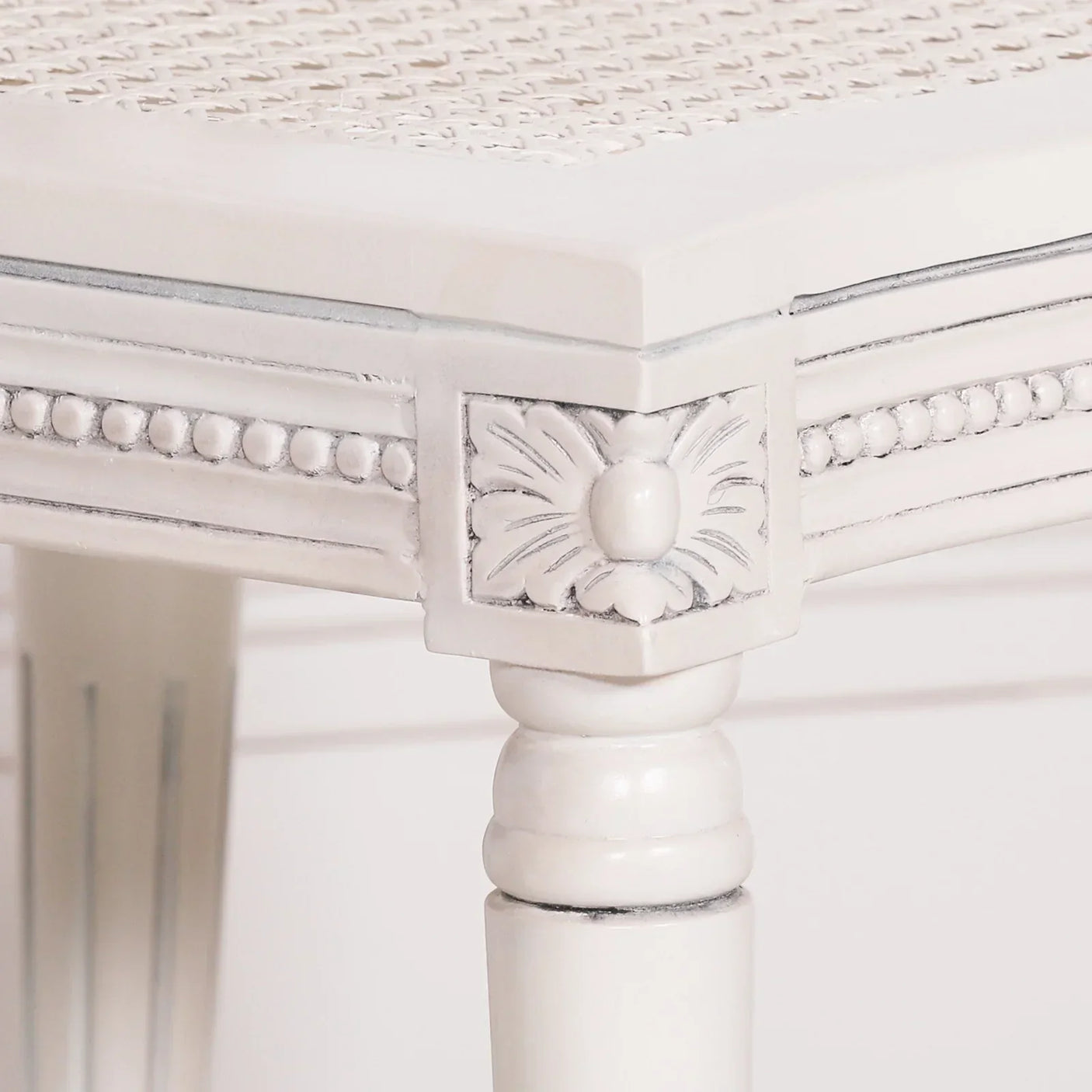White wooden table with carved floral corner detail and ornate beaded edge
