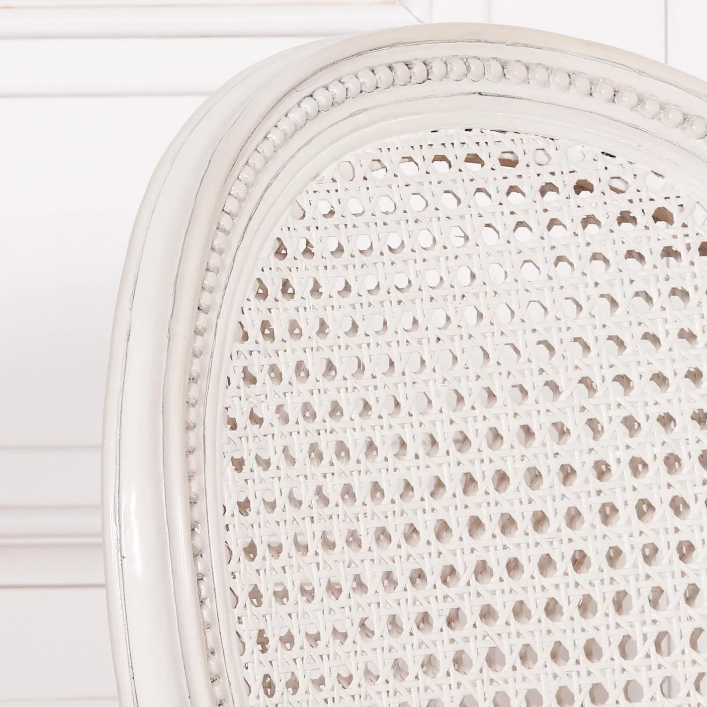 White rattan dining chair backrest with carved wooden frame and woven cane detail