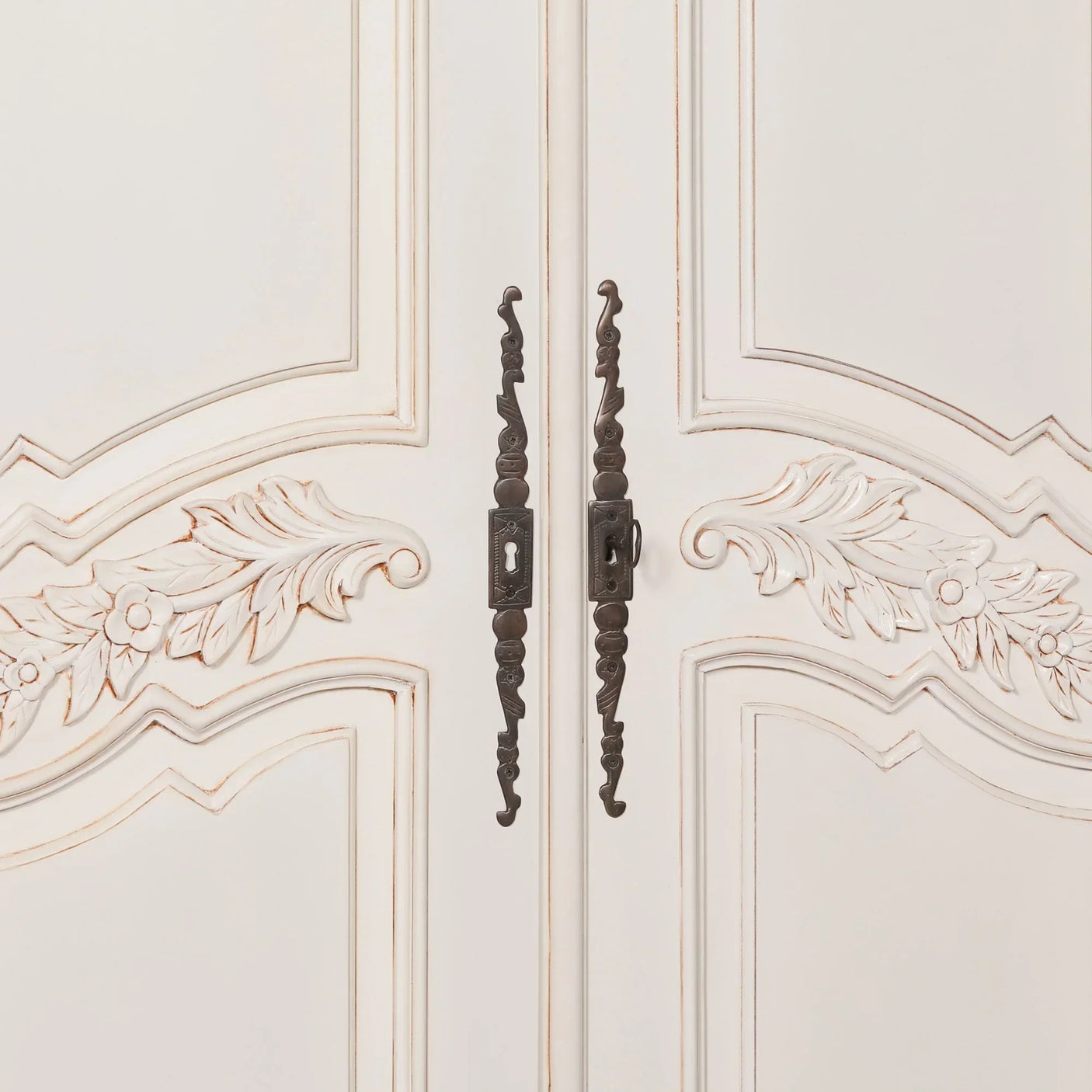 Cream painted wardrobe doors with floral carvings and antique metal handles