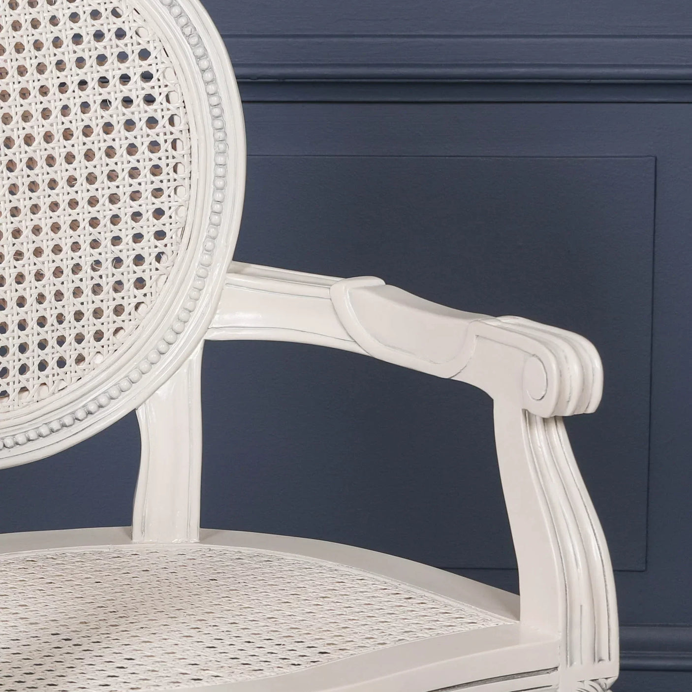White rattan dining chair with cane backrest and seat, close view of armrest detail
