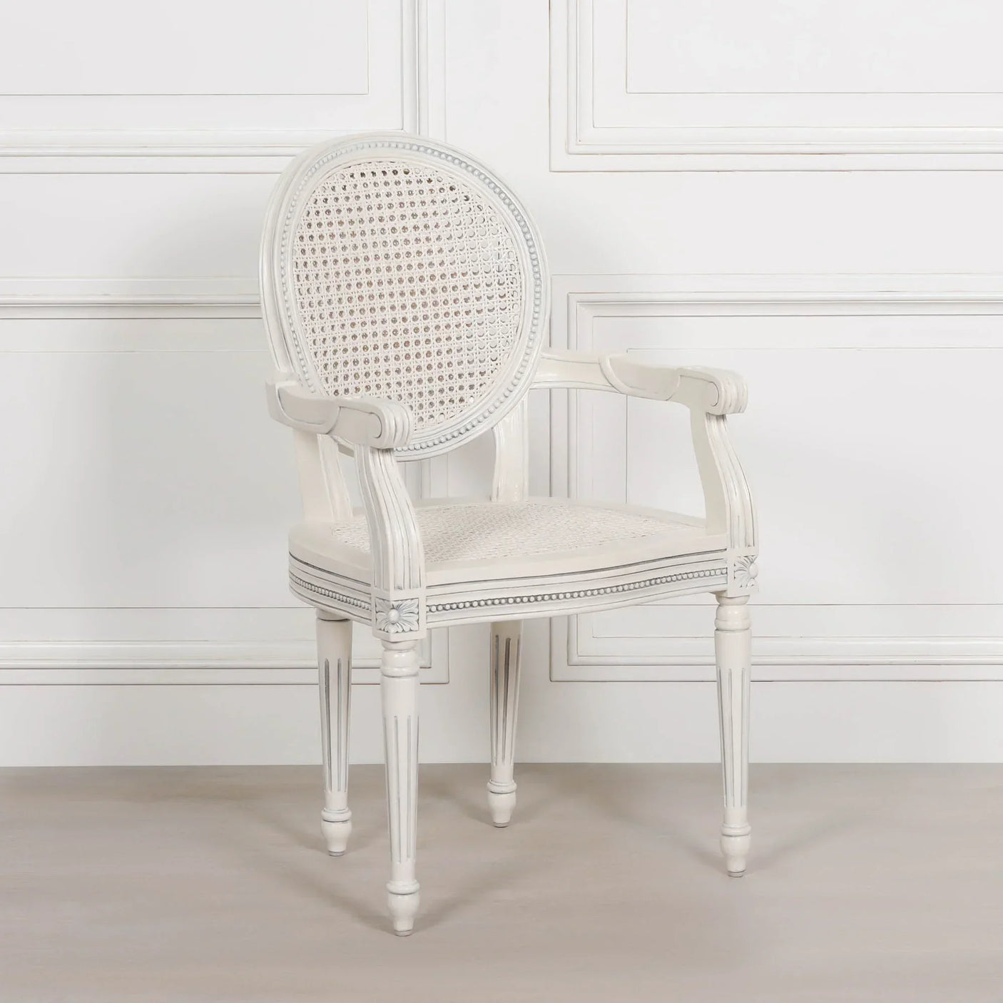 White wooden armchair with cane backrest and seat, carved legs and classic style
