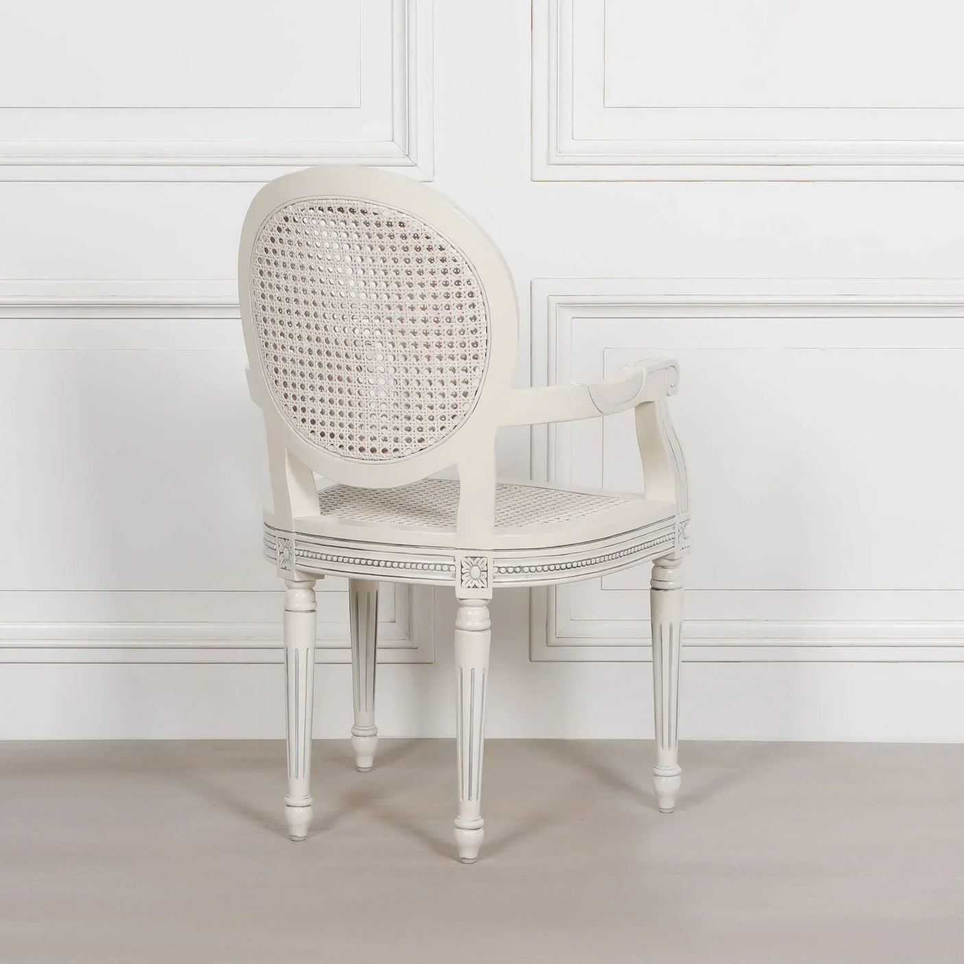 Classic white cane back dining chair with upholstered seat and carved wood details, rear view
