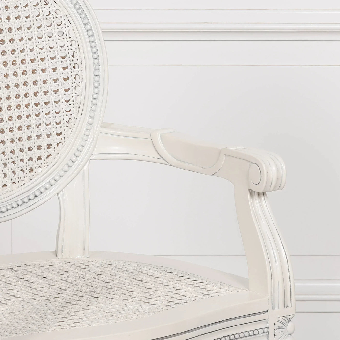 White wooden cane dining chair with rounded backrest and armrest detail