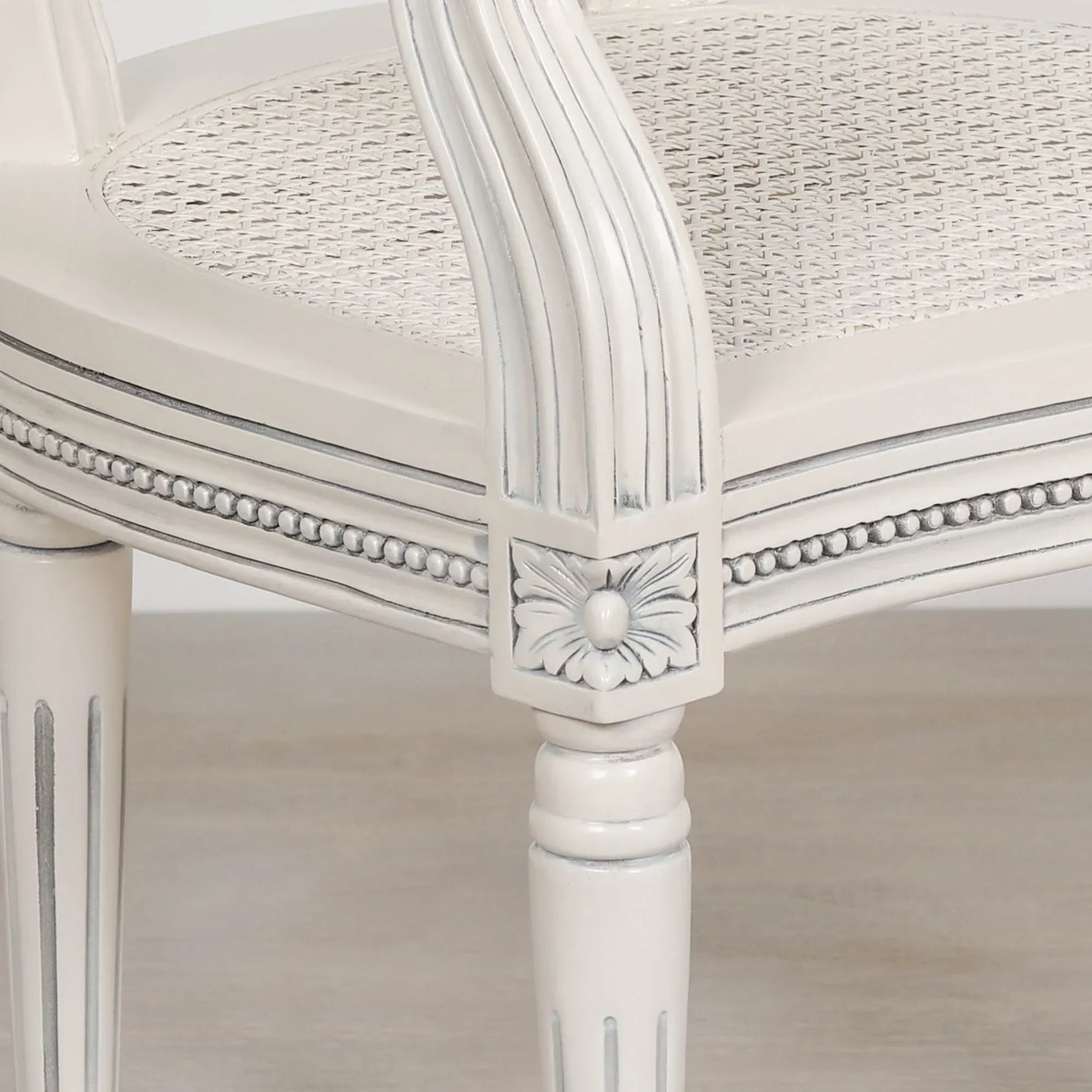 White wooden dining chair with carved floral detail and rattan seat close-up
