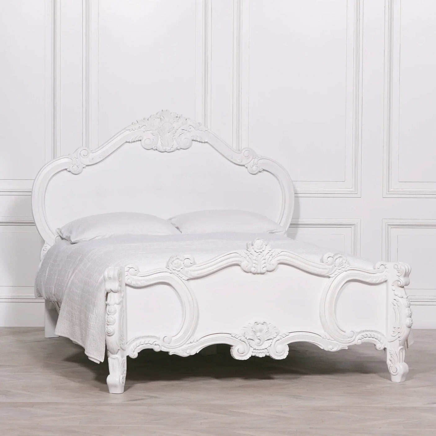 White carved wooden bed frame with ornate headboard and footboard, styled with white bedding