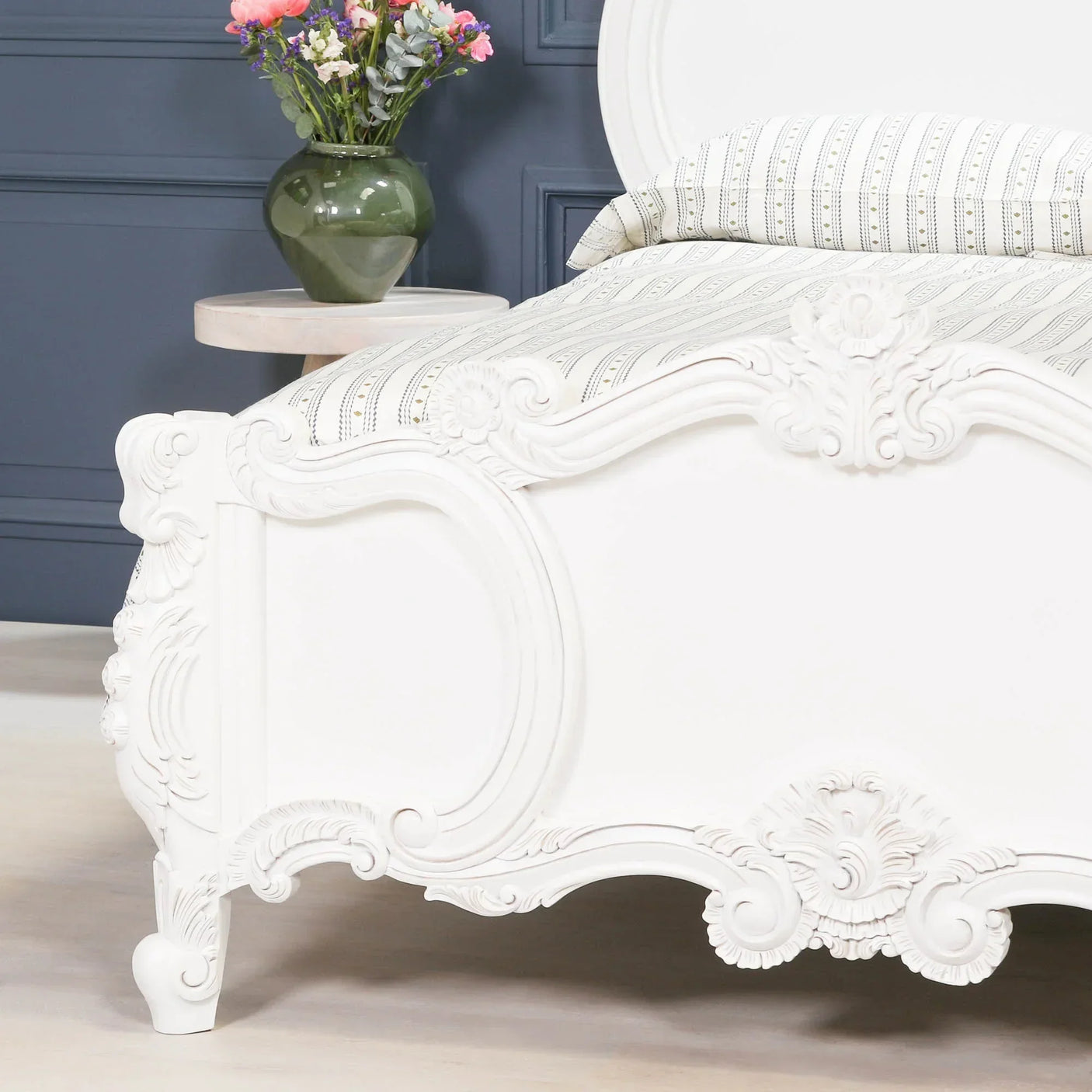 White carved wooden bed frame footboard with floral detail in bedroom setting