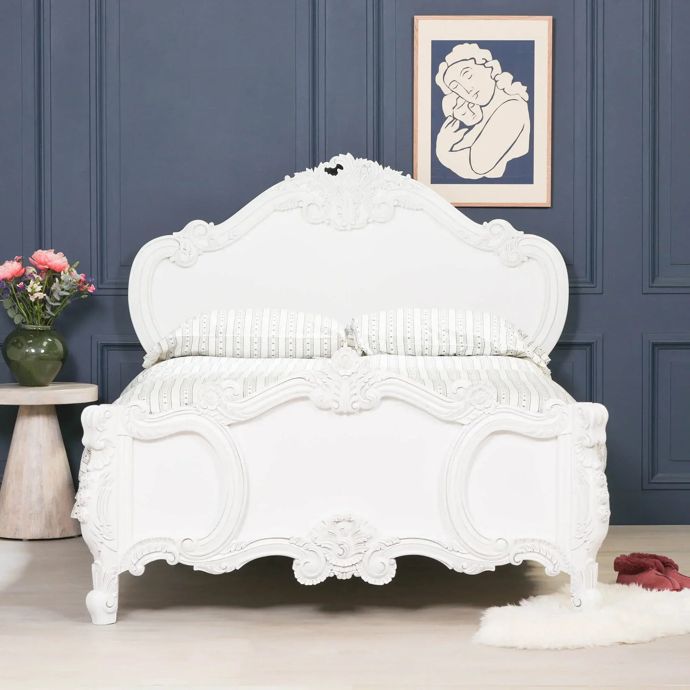 white carved wooden bed with ornate detailing in front of a dark panelled wall
