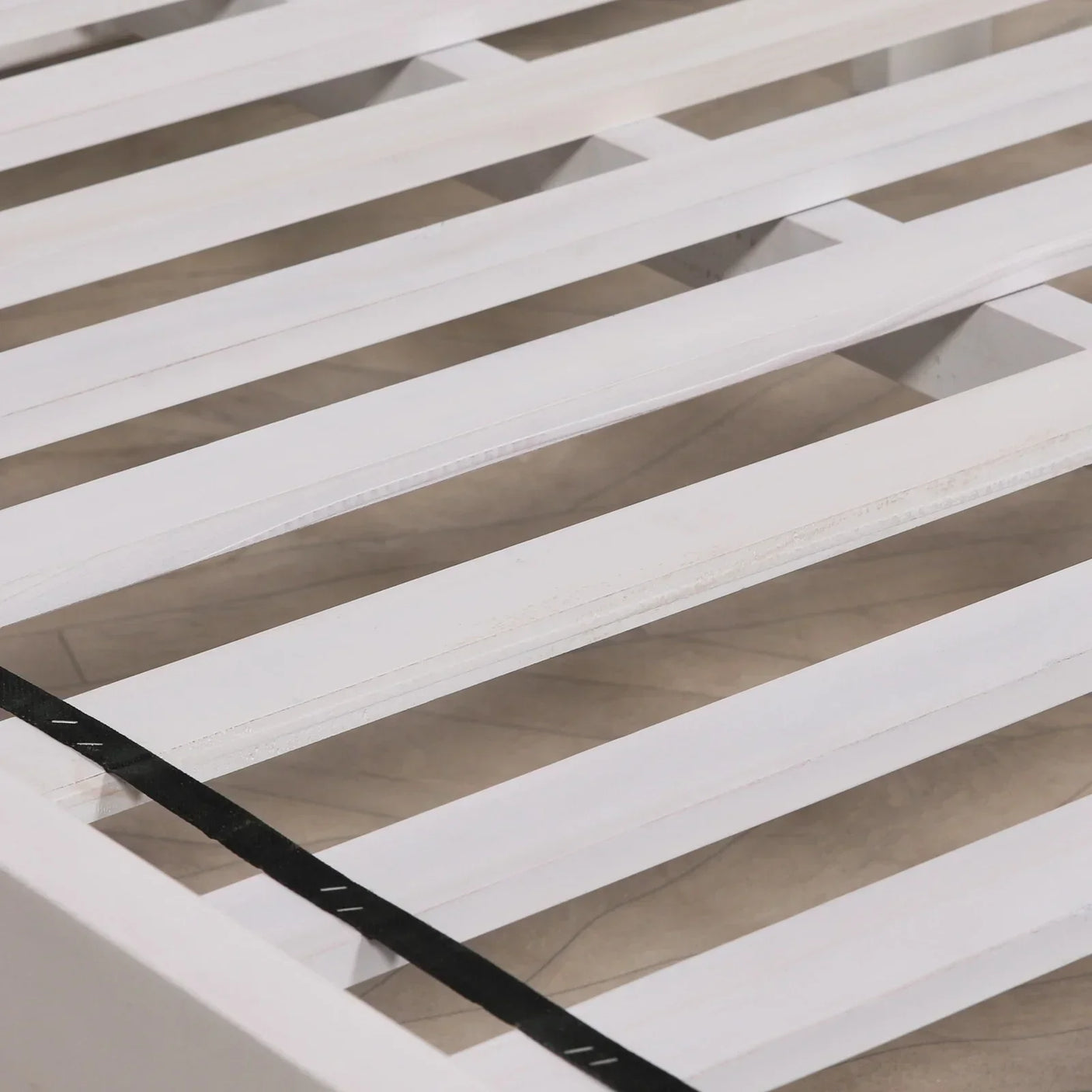 White wooden bed frame slats with black support strap, close-up view