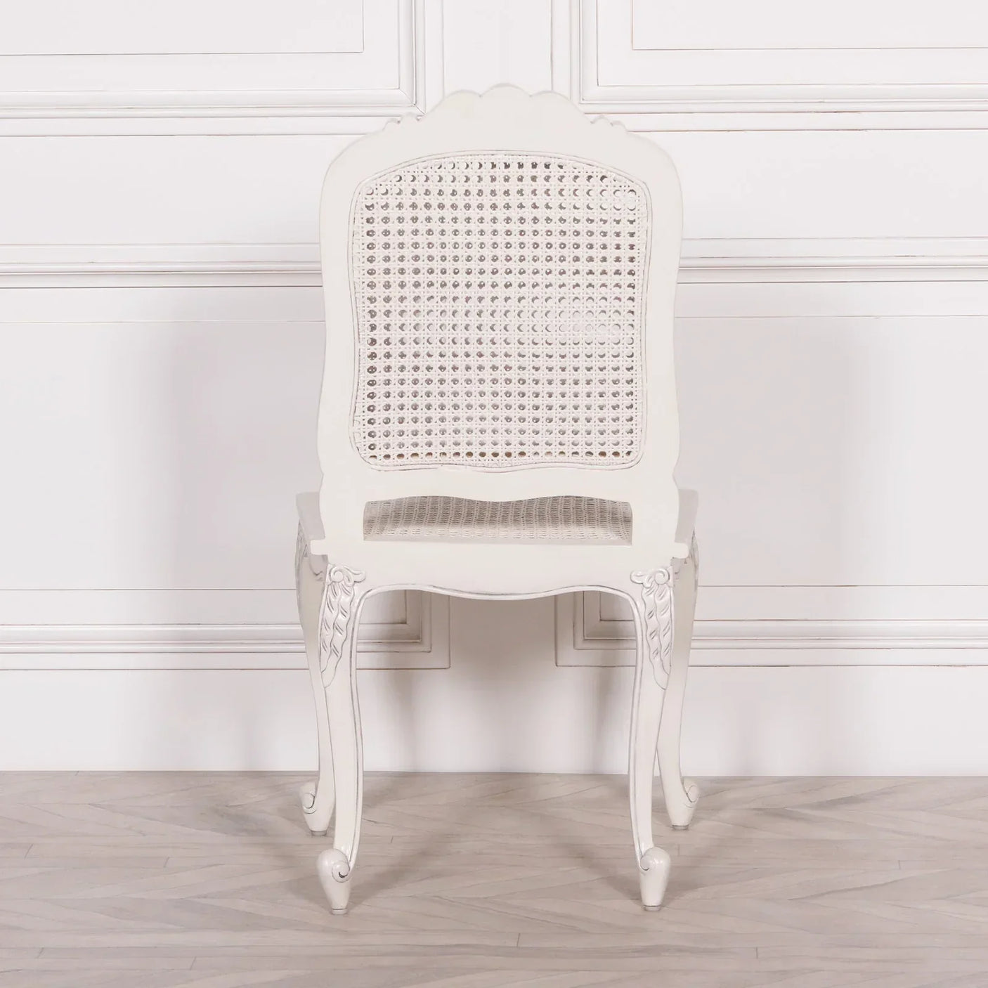 White wooden dining chair with cane backrest and seat, shown from the back