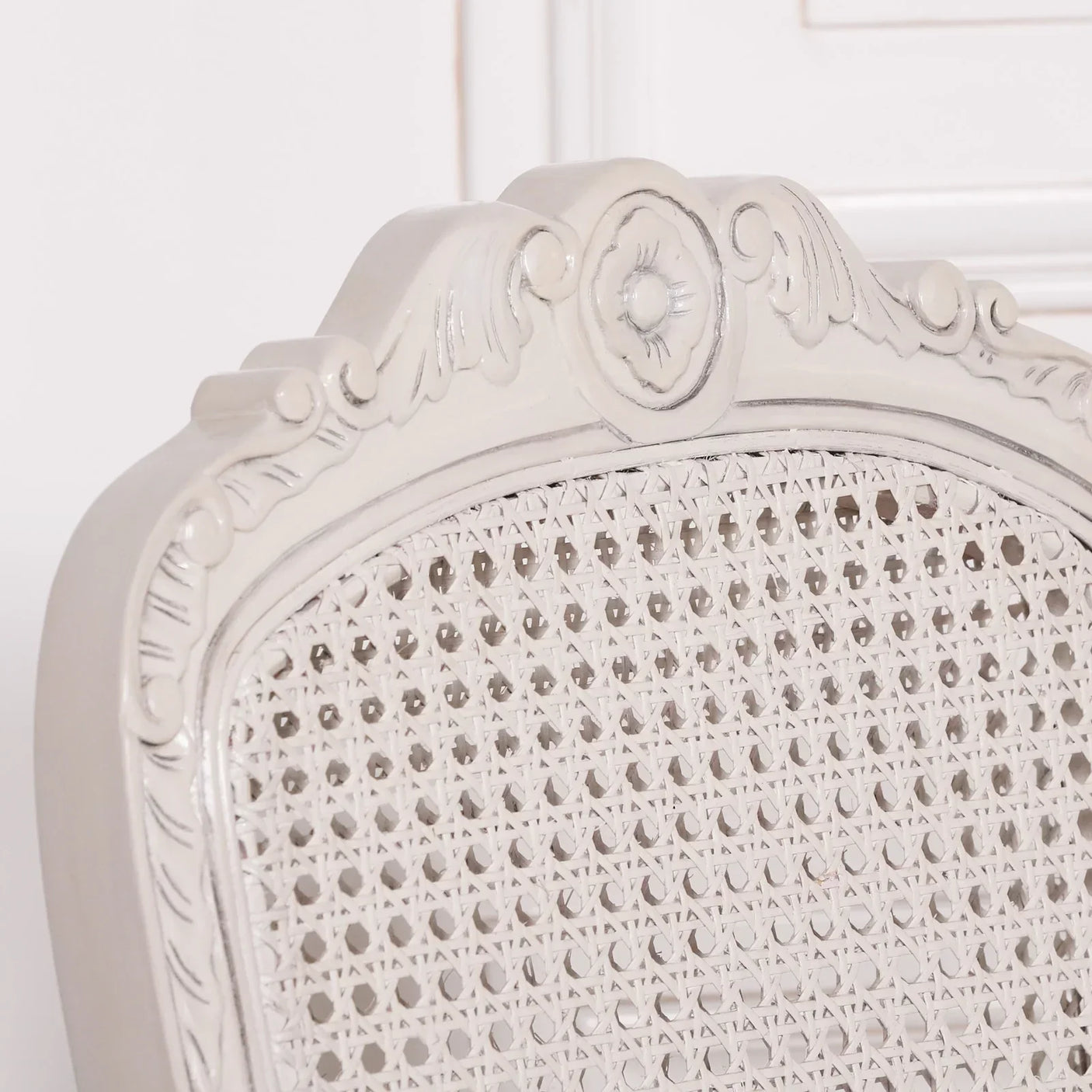Close-up of carved wooden dining chair backrest with white cane detail