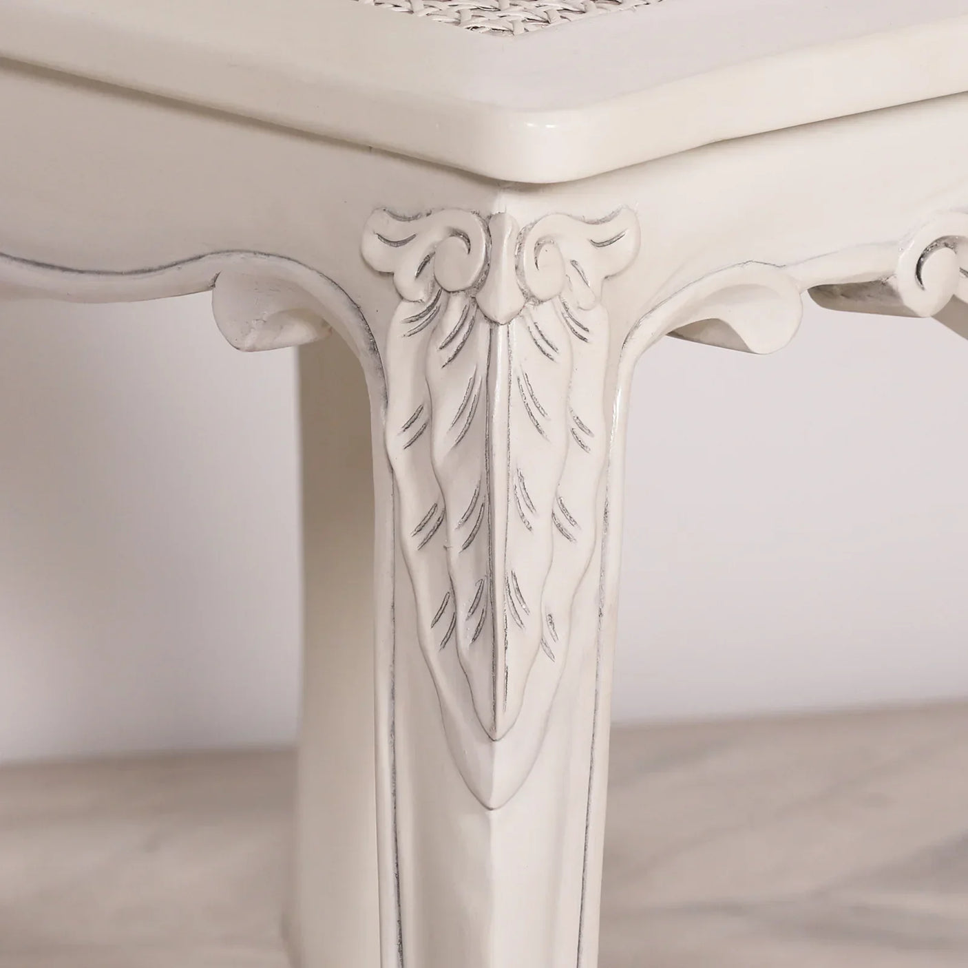 Close-up of carved white wooden table leg with ornate detailing and smooth finish