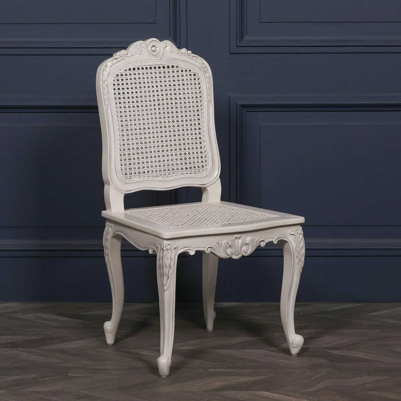 White cane dining chair with carved wood frame and curved legs on wood floor
