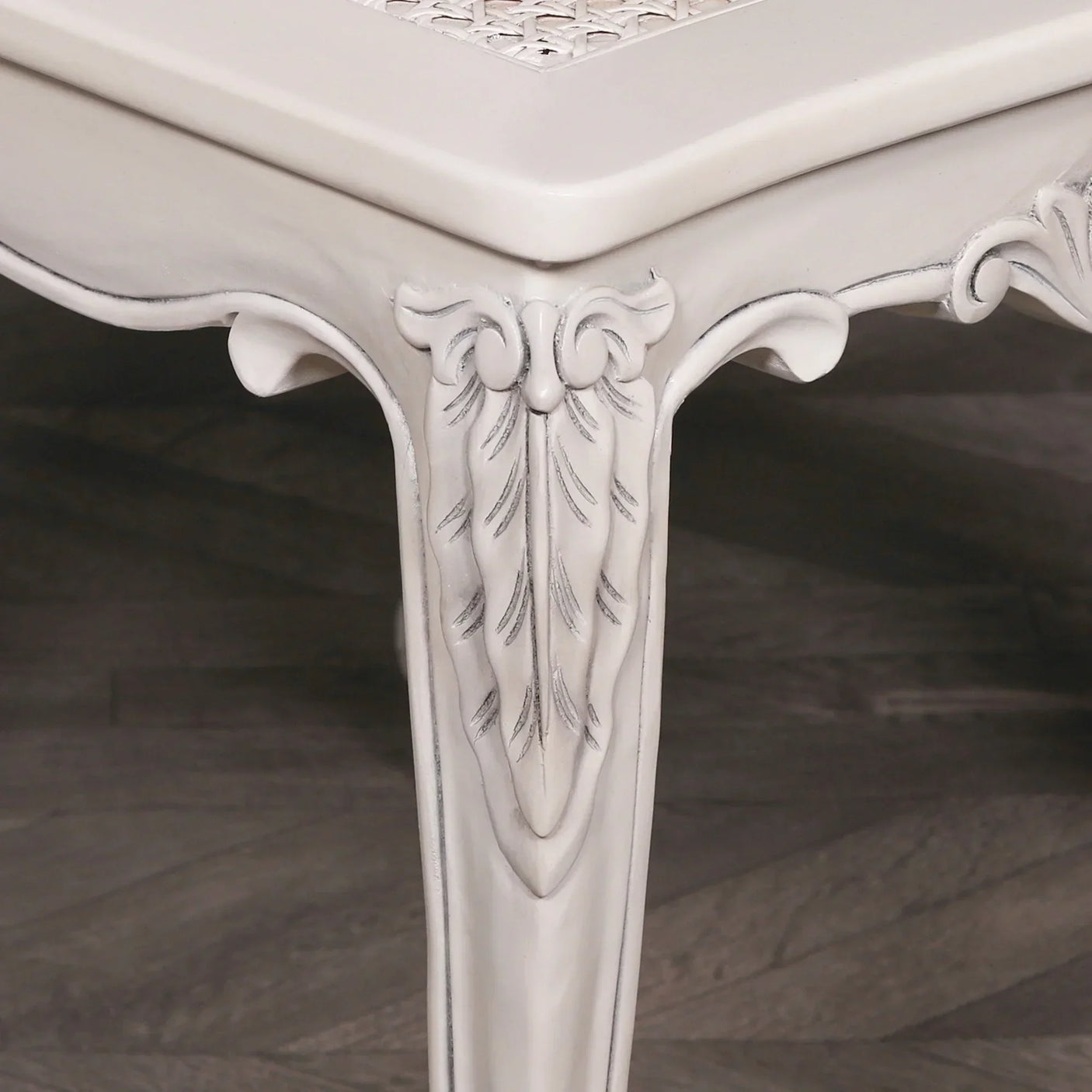 Carved wood dining table leg with white painted finish and leaf motif detail
