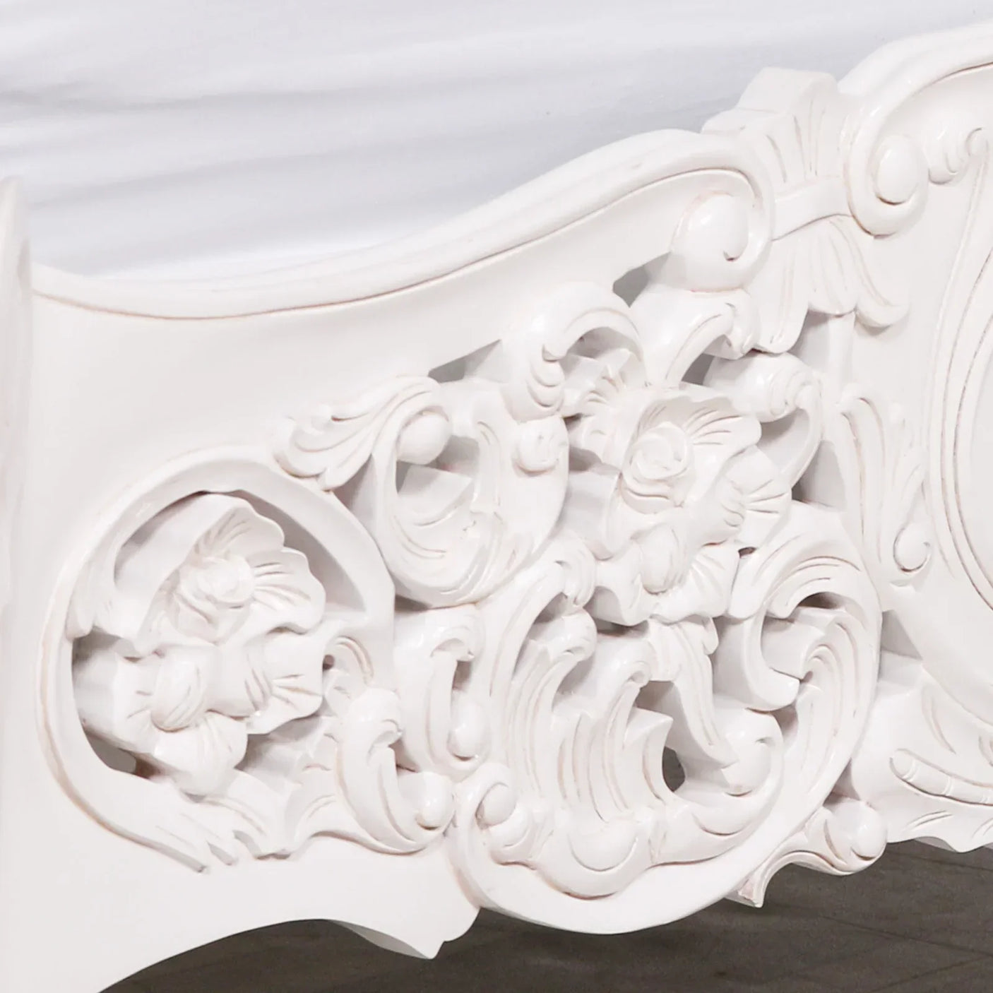 White carved wood bed frame with ornate floral detailing