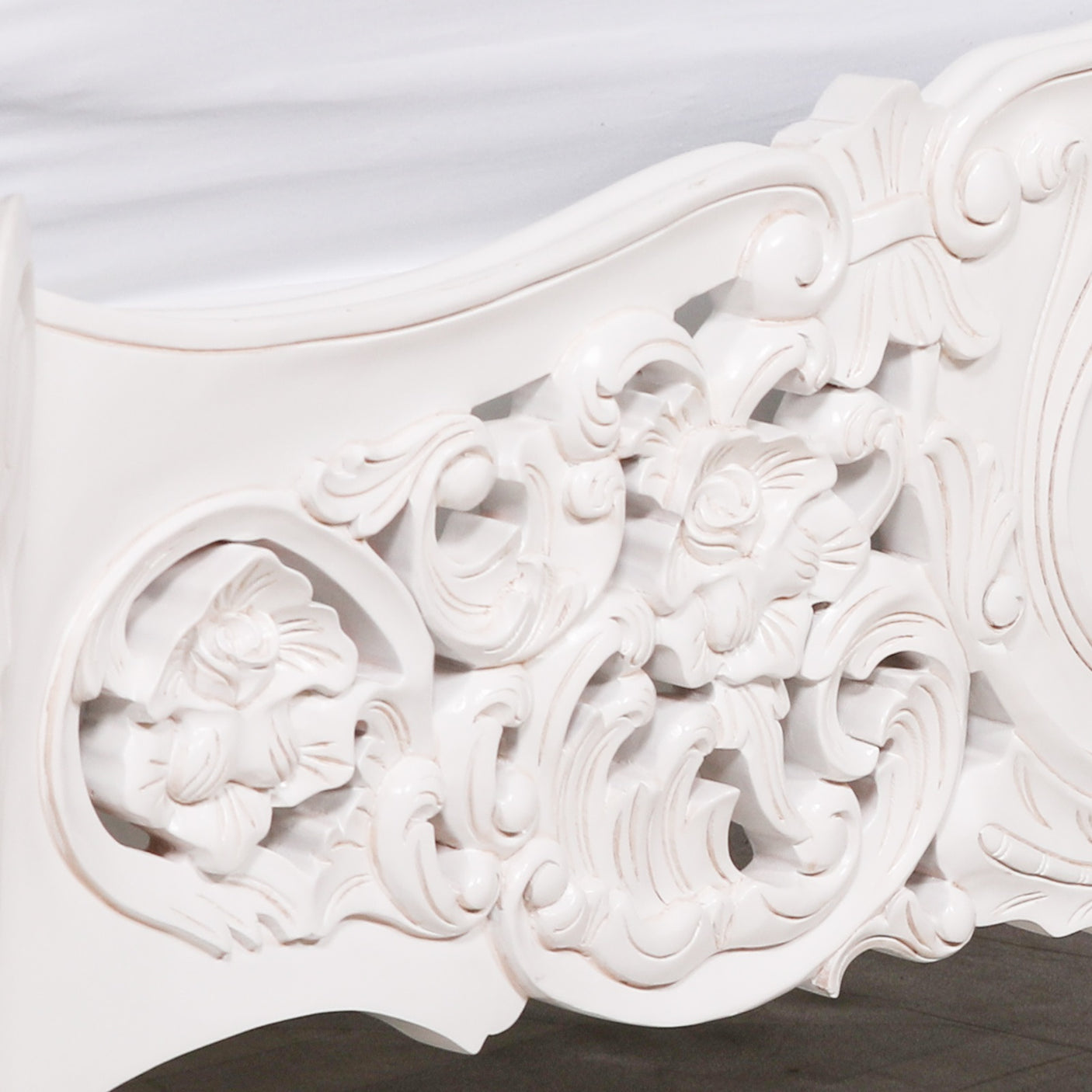 Close-up of an ornate white decorative element with intricate carvings on a plain background