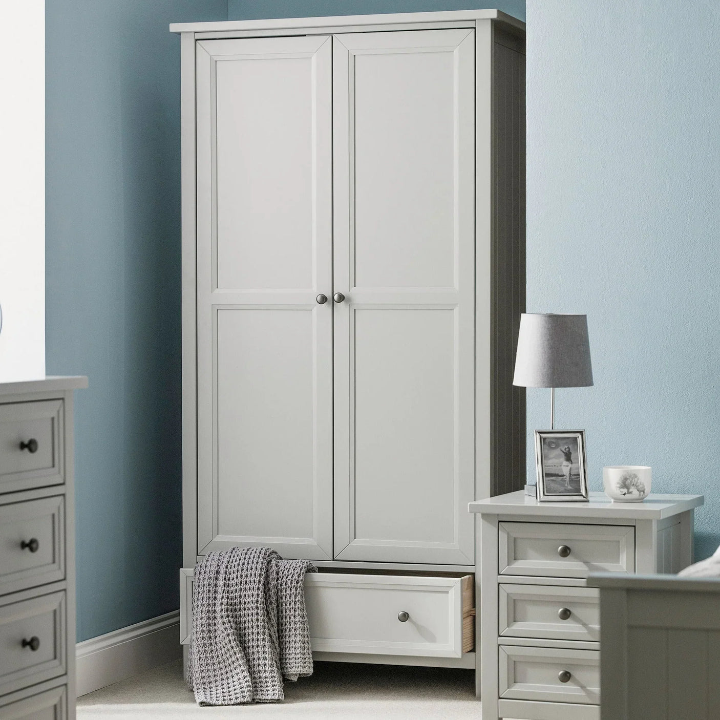 Grey two door wardrobe with bottom drawer open in modern bedroom setting