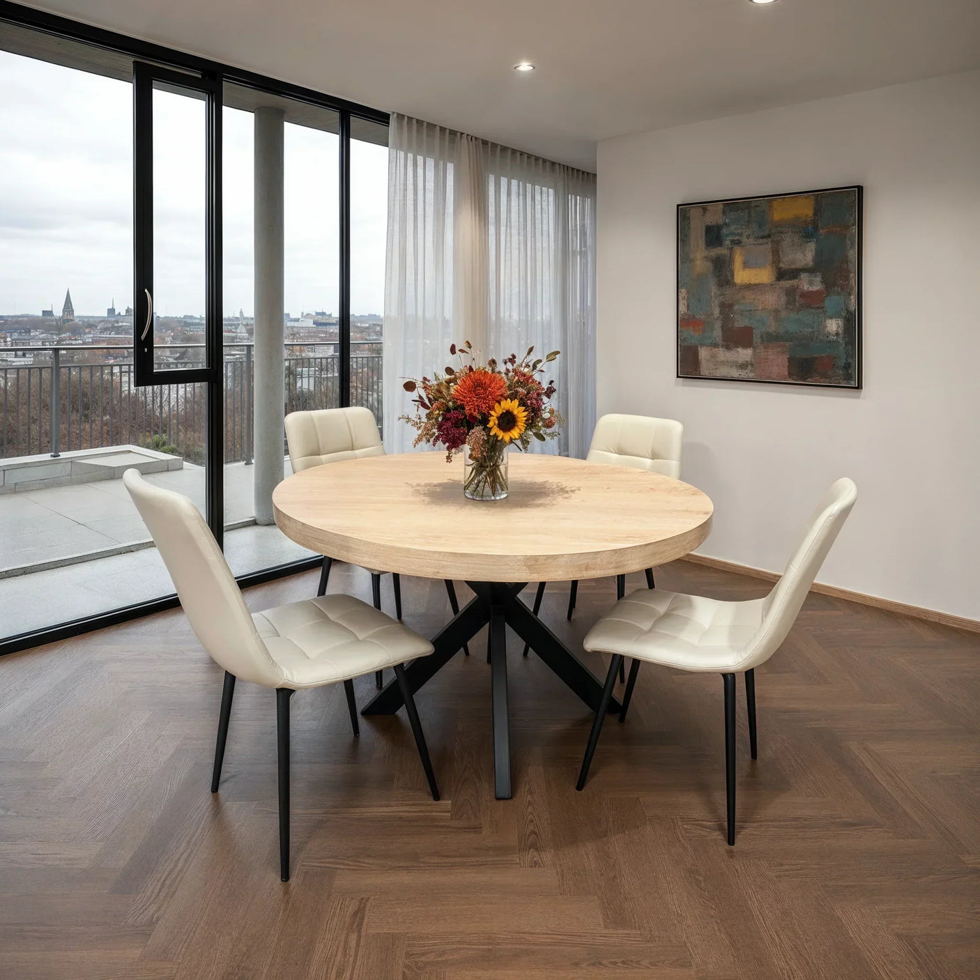 Round wooden dining table with taupe chairs and a floral centerpiece in modern dining room