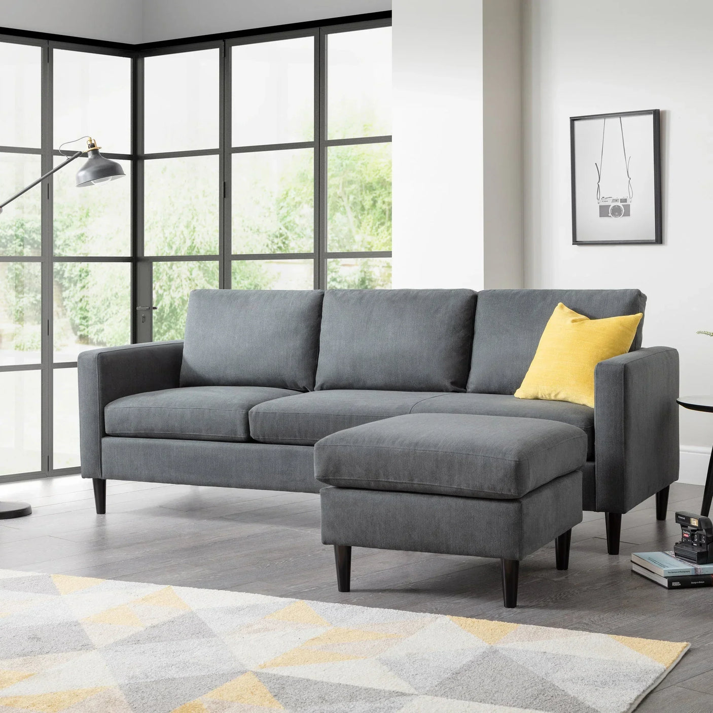 Grey corner sofa with matching ottoman and yellow cushion in modern living room setting