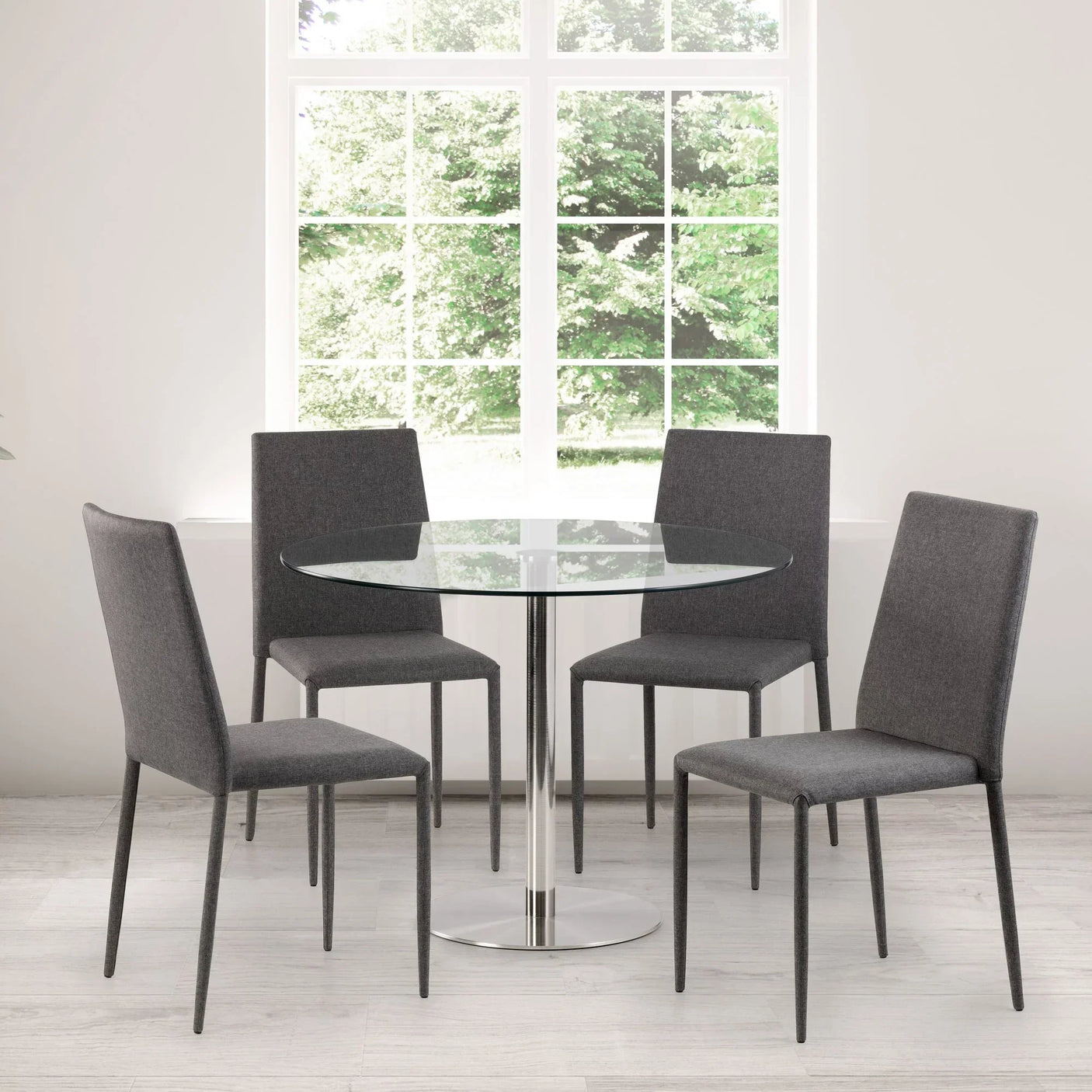 Round glass dining table with chrome base and four grey fabric chairs in modern dining room