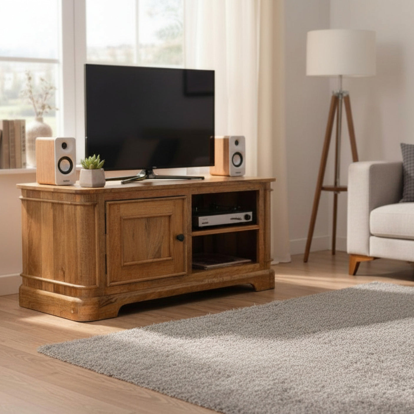 Wooden TV stand with a television, speakers, and decorative items in a living room.