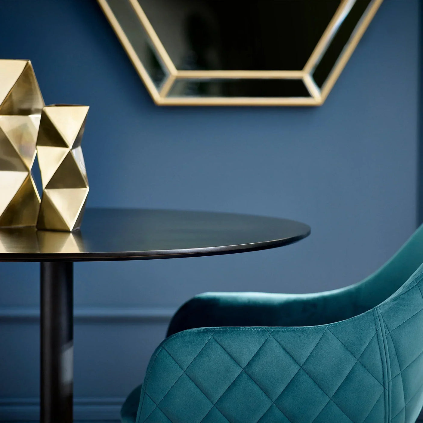 Nero round dining table with black top, gold geometric decor and teal quilted chair