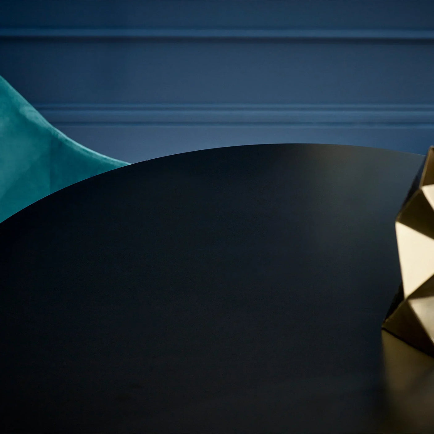 Black dining table top with geometric gold decor and teal chair