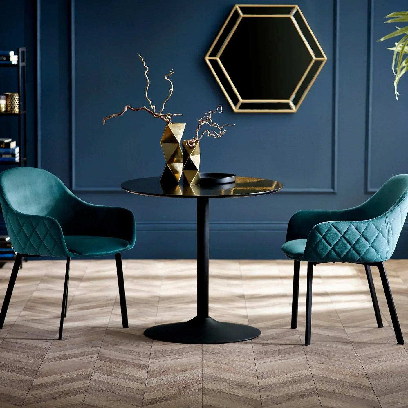Nero 90cm round dining table with two teal velvet Lima chairs in a modern styled room