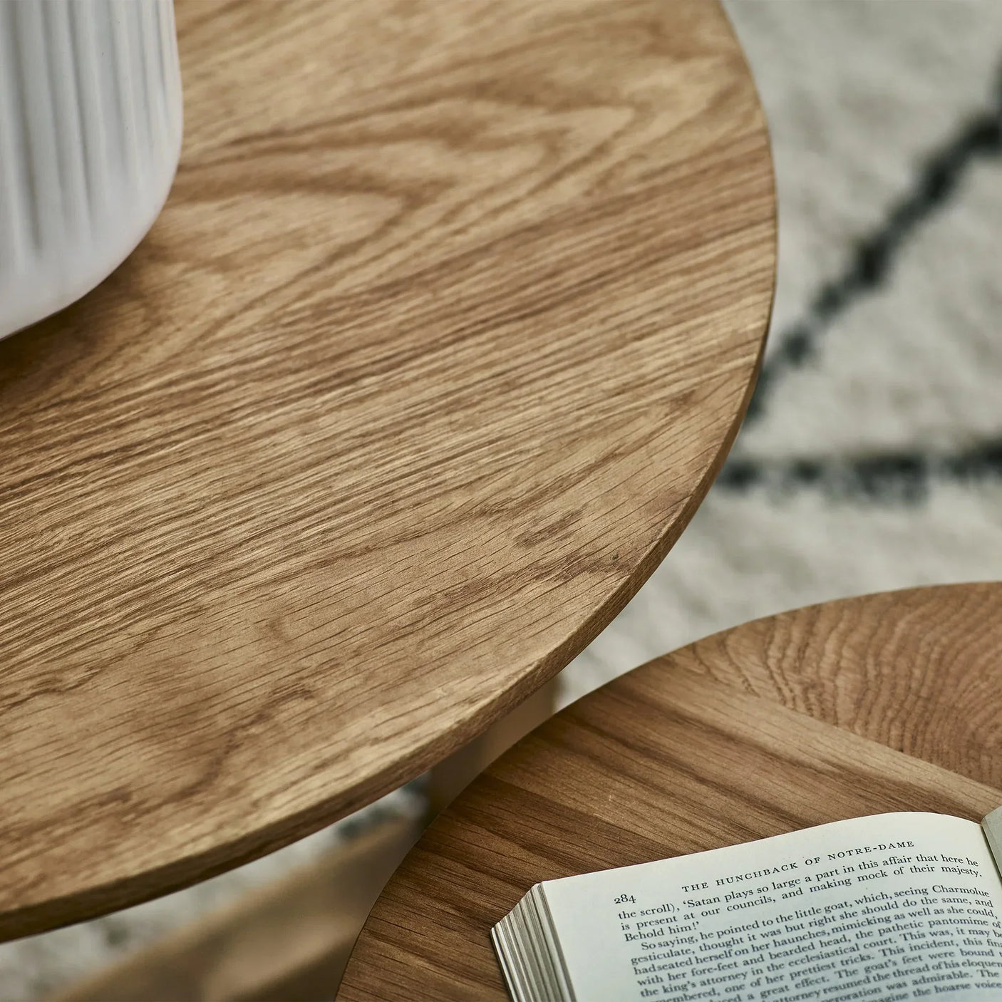 Closeup of oak nest of tables showing wood grain and book on tabletop
