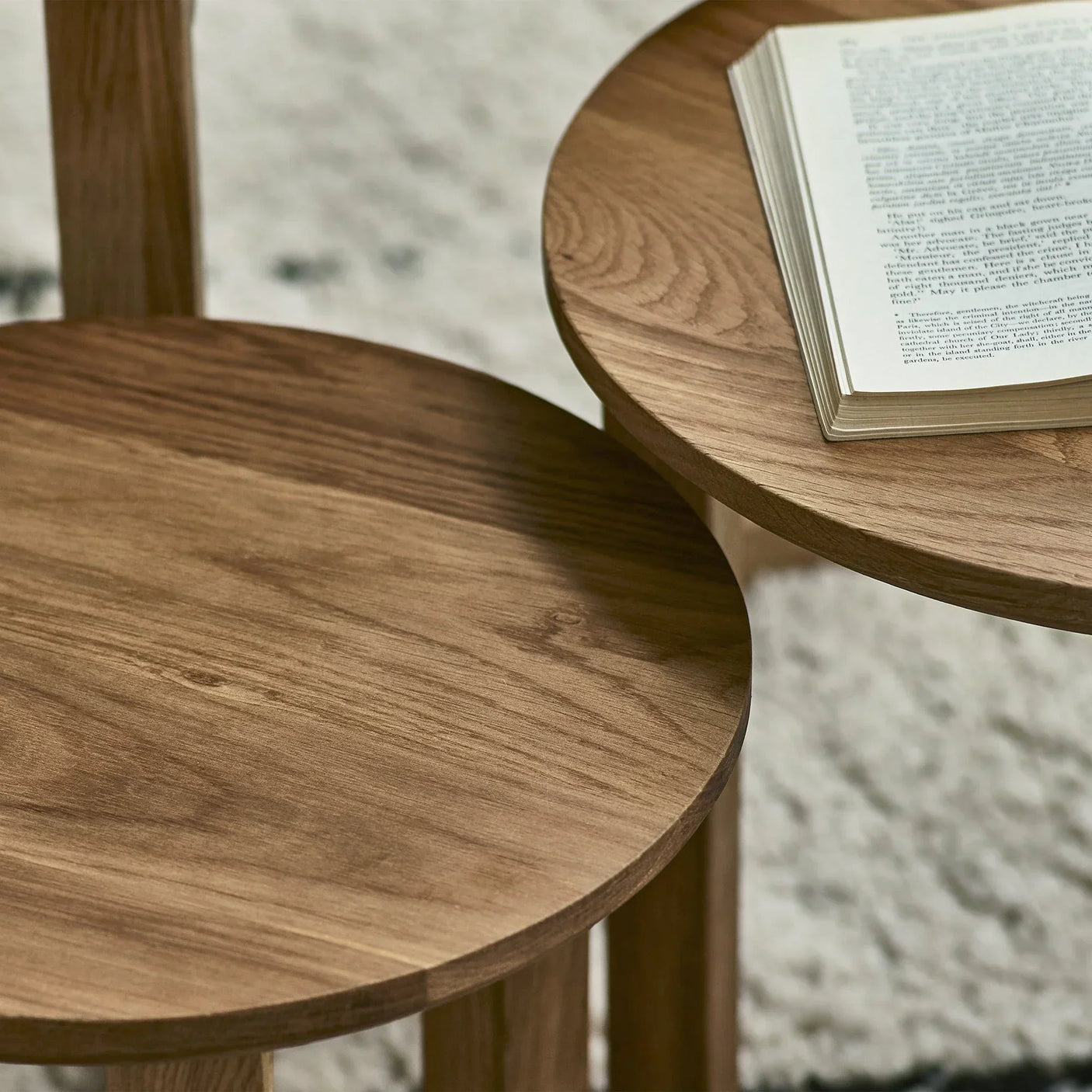 Nest of tables with natural wood grain detail, book placed on round tabletop