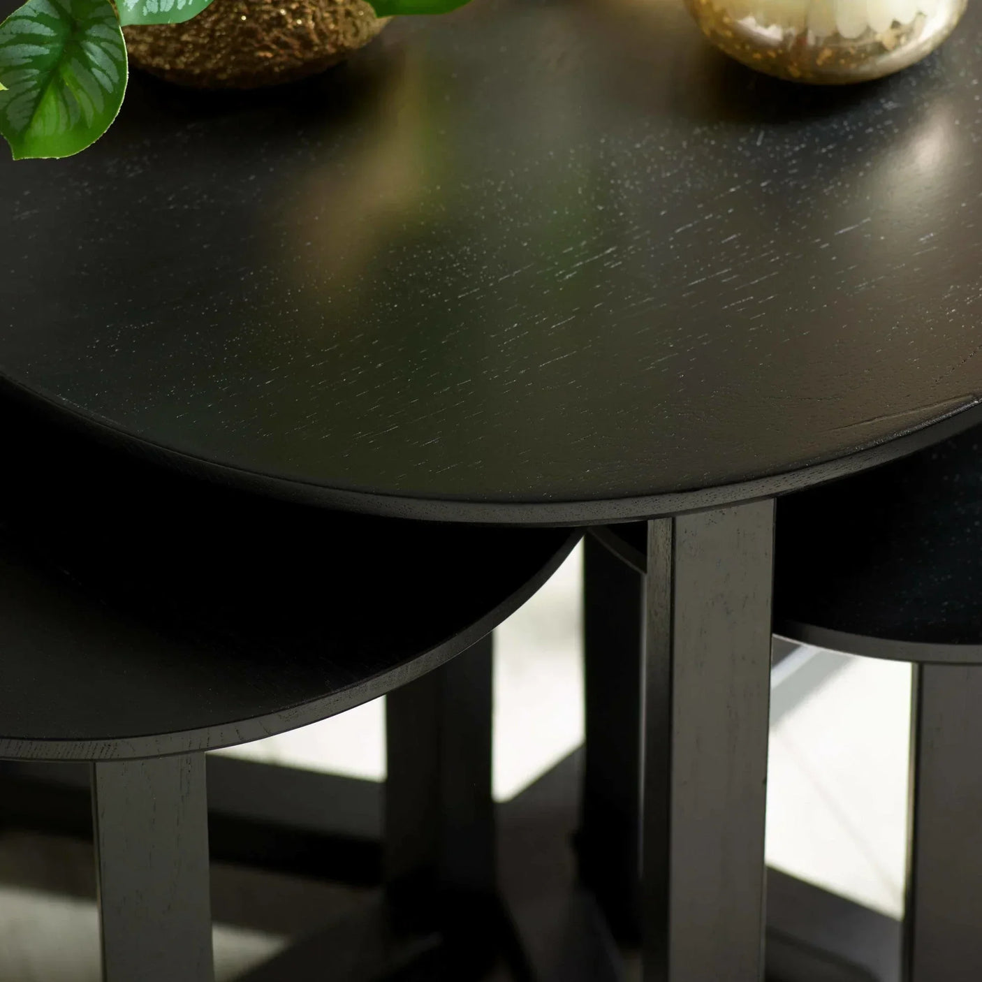 Black wood nesting tables with round tops and visible wood grain detail