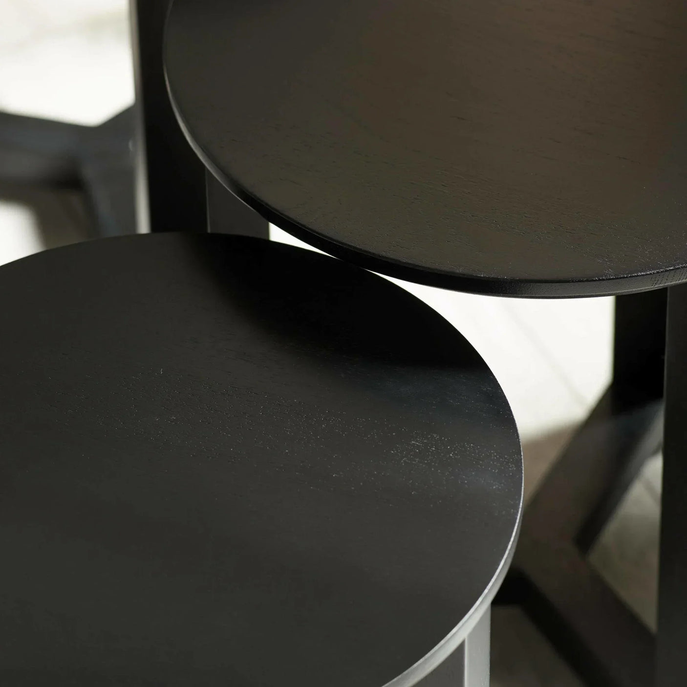 Close-up of black wooden nesting tables with round tops and subtle wood grain texture