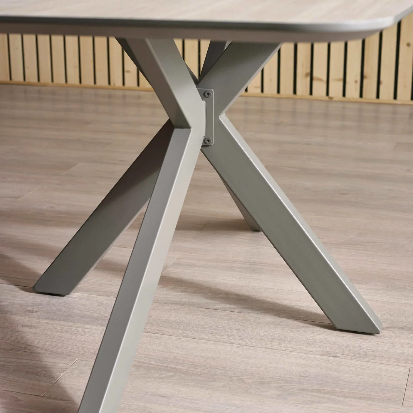 Grey metal dining table legs with cross base detail on laminate wood floor