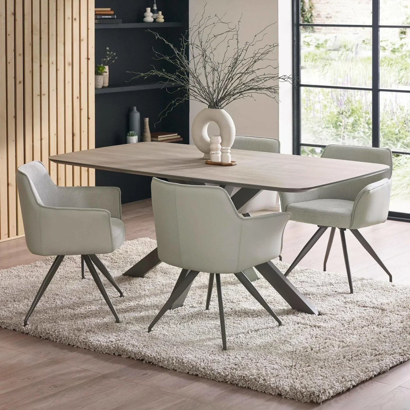 Modern dining table set with grey swivel chairs on a rug in a bright dining room
