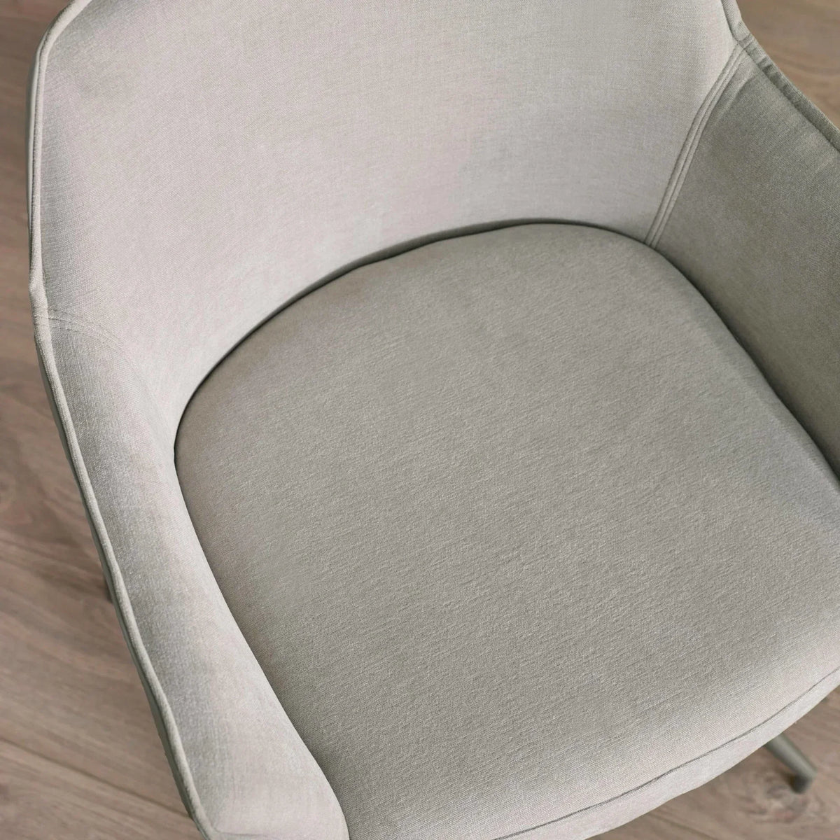 Grey fabric armchair close-up with cushioned seat and curved backrest on wood floor
