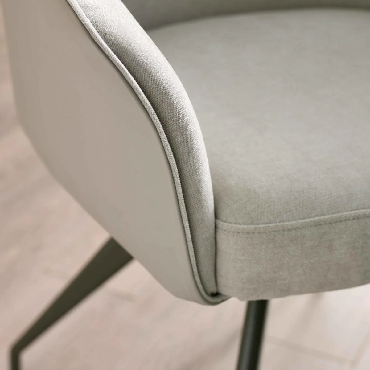 Close-up of grey fabric dining chair with soft upholstery and angled metal leg