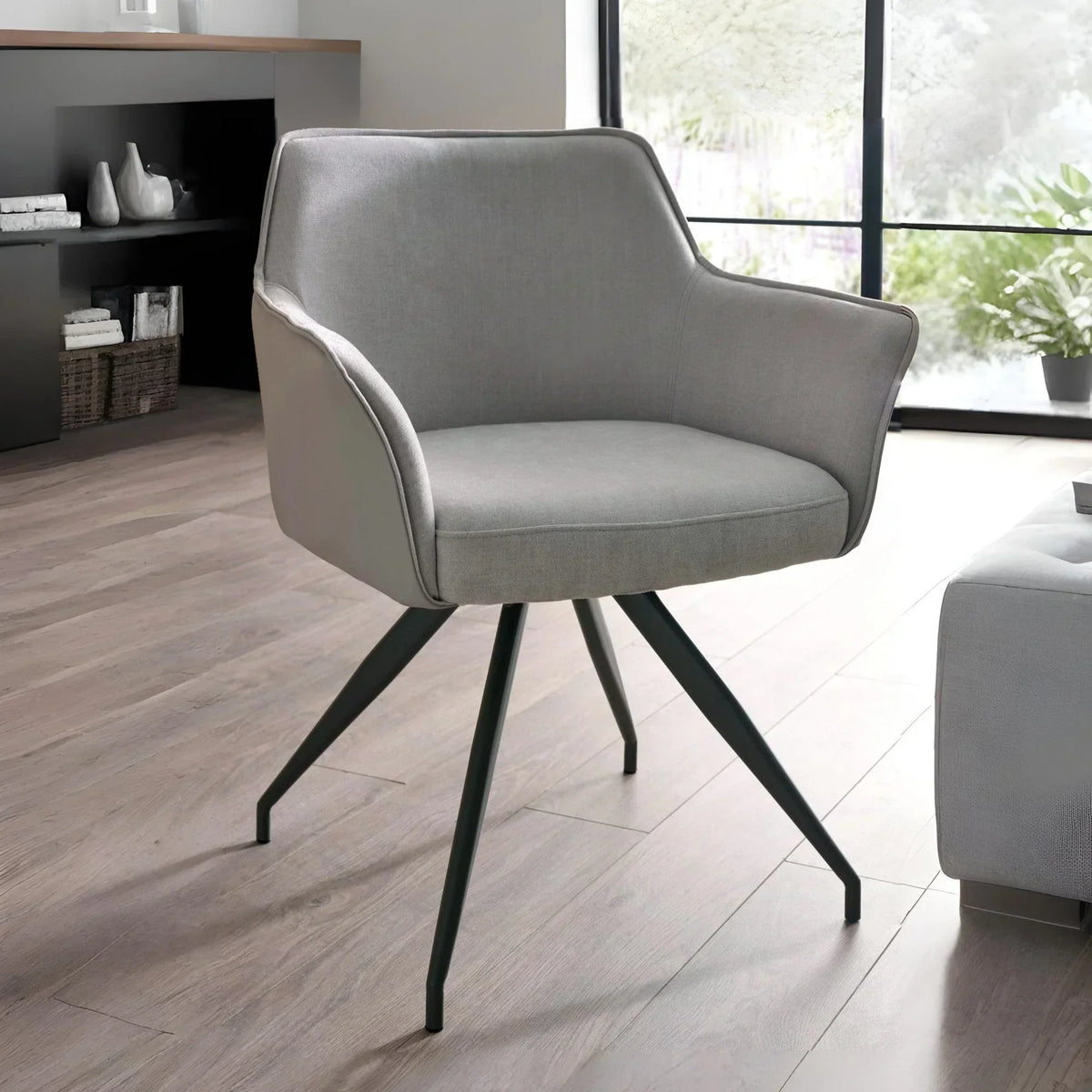 Grey upholstered accent chair with black metal legs in modern living room setting