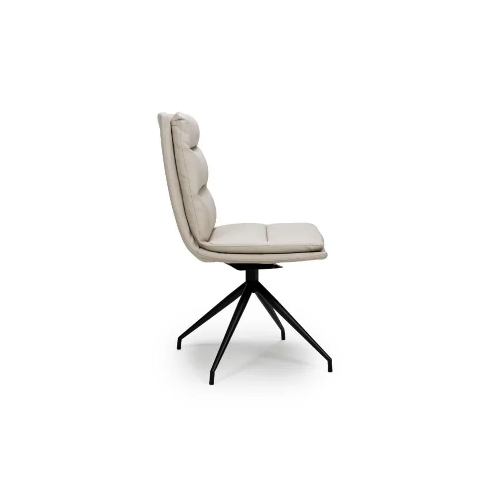 Beige dining chair with padded seat, tufted backrest, and black metal swivel base side view