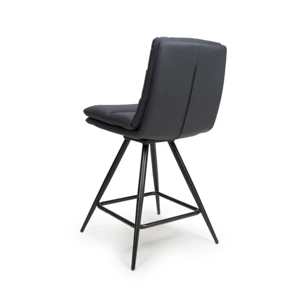 Black barstool with padded seat, angled metal legs and footrest, rear view