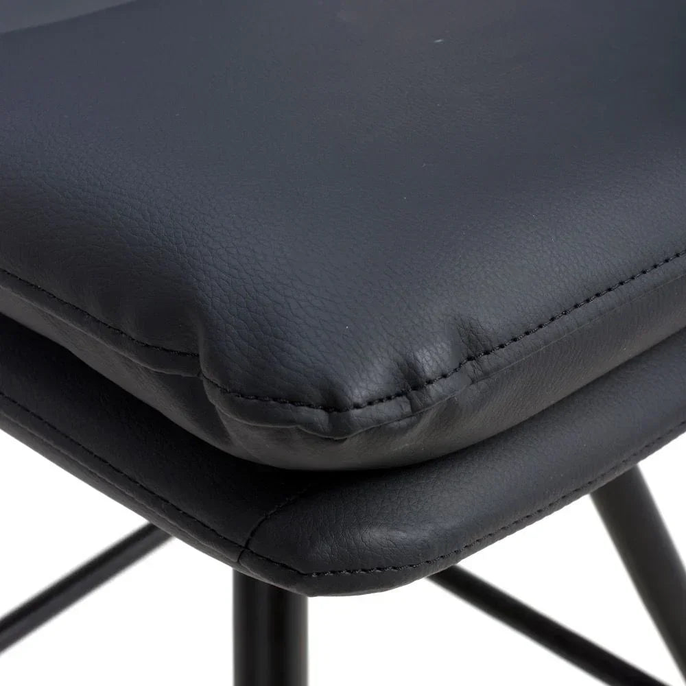 Closeup of black faux leather dining chair cushion with metal legs