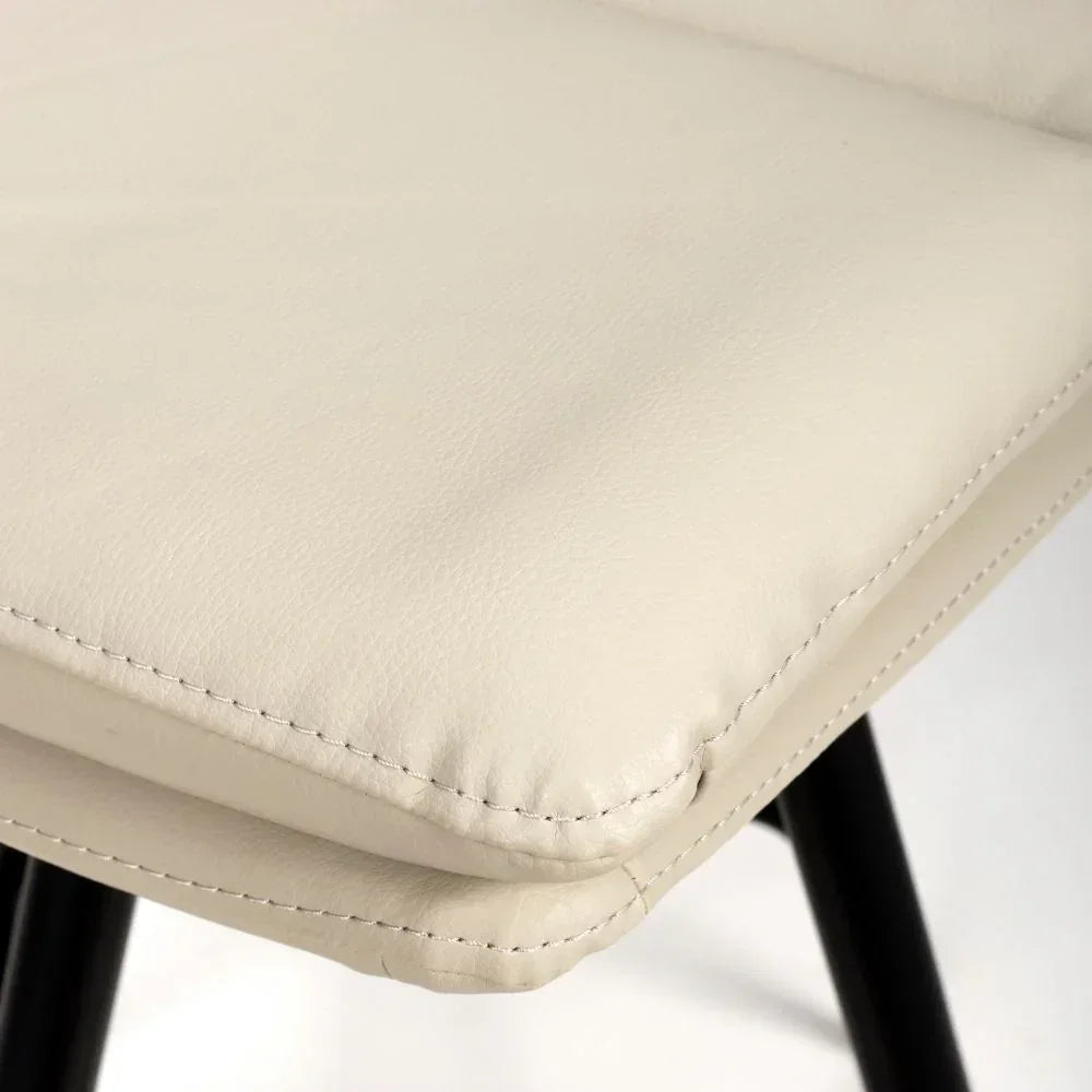 Closeup of cream faux leather dining chair seat with black legs and visible stitching