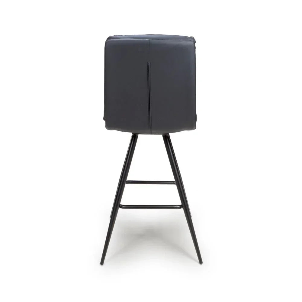 Black bar stool with padded backrest and slim metal legs, rear view