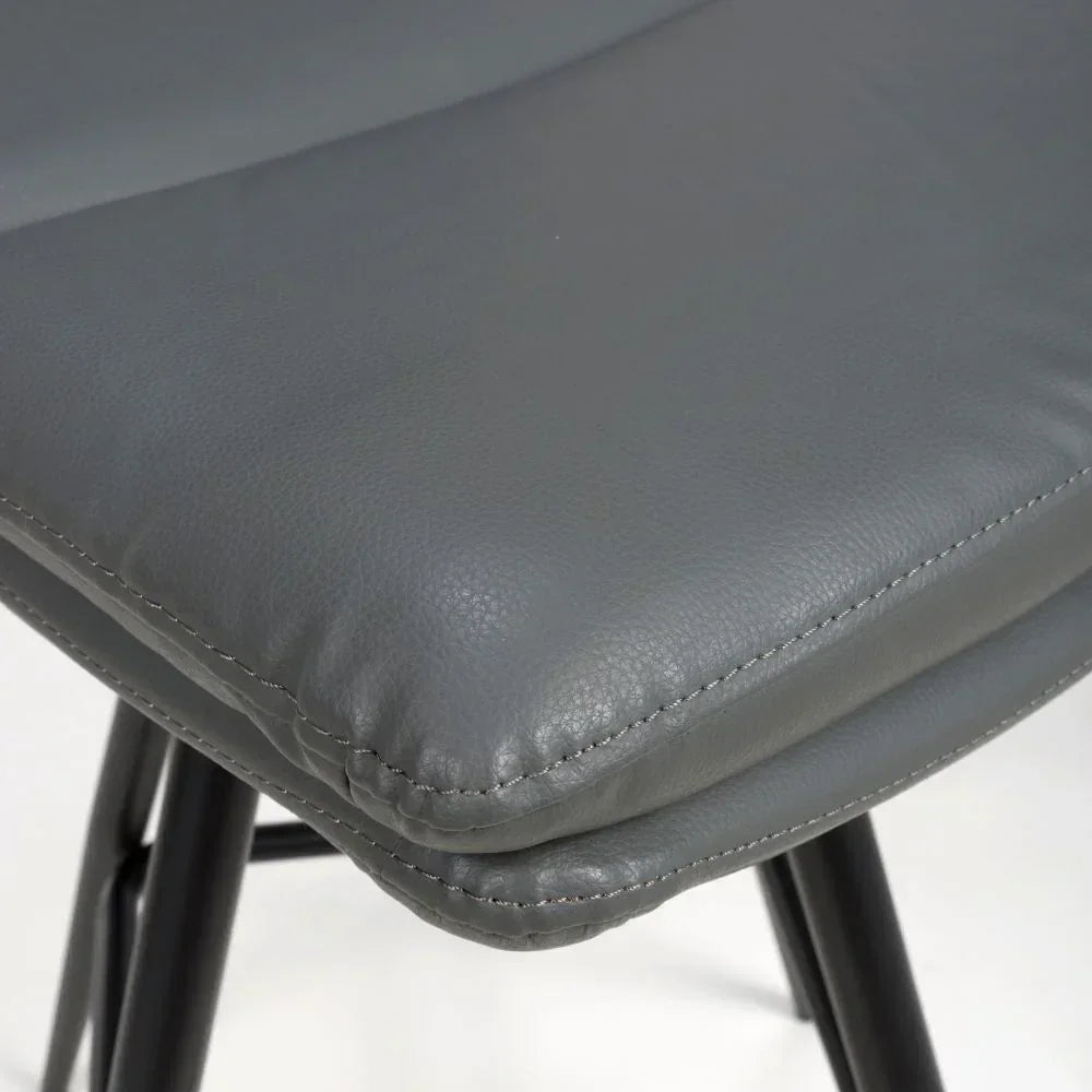 Close-up of grey faux leather dining chair seat with black legs and visible stitching